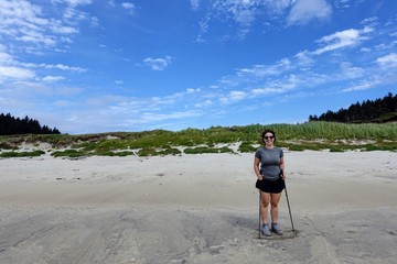 A female hiker exploring the sandy beaches of nels bight and experimental bight, surrounded by forest and the pacific ocean, along the beautiful cape scott trail on Northern Vancouver island