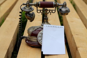 
Notepad and vintage telephone, on wooden beams.