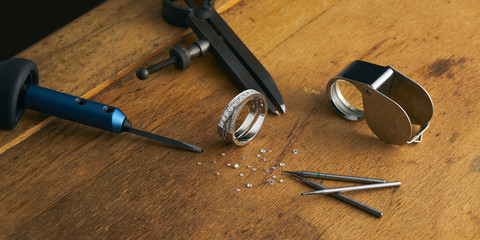 Workplace of a jeweler. Tools and equipment for jewelry work on an antique wooden desktop....