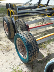 Row of Dinghy Sailing Wagon Wheels on Sand. Boat trailers. Beach carts background.