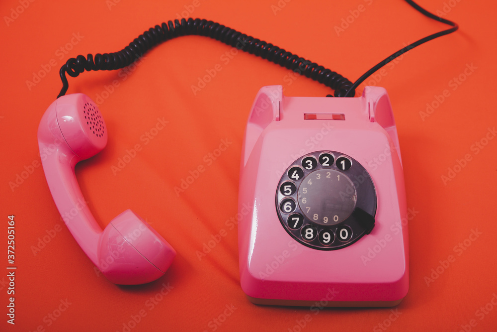 Wall mural vintage pink telephone with orange background