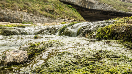 Arroyo discurre entre rocas rápidamente a su desembocadura.
