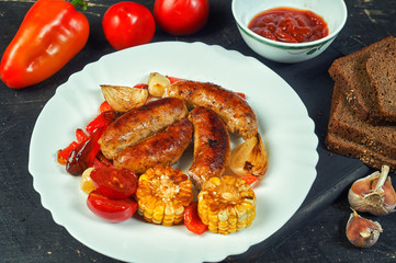 fried homemade sausages with vegetables on a plate .cooking at home . the view from the top