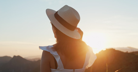 Woman wear straw hat and look at the sunset view on mountain
