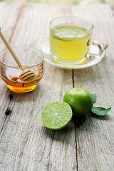 Honey lime drink on wood table with fresh lime and honey.
