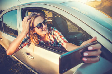 young woman makes selfie on the phone from the car window. travel in nature