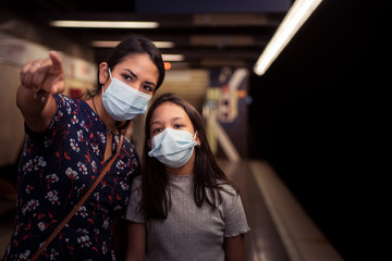 Fototapeta na wymiar Concept of transportation on the new normal during coronavirus infection. Mother and daughter wearing surgical mask on the underground.