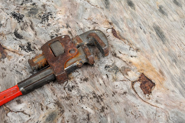 Long nose pliers and adjustable wrench on wood grain background. 