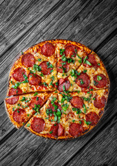 Pepperoni Pizza with Mozzarella cheese, salami, Tomato sauce, pepper, Spices and Fresh basil. Italian pizza on wooden table background