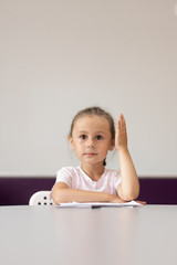 Little girl raising her hand up in class