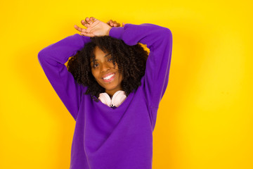 Portrait of beautiful brunette female looks with excitement at camera, keeps hands raised over head notices something unexpected, isolated over gray wall. Lovely woman reacts on sudden news.