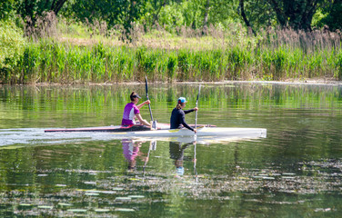 Fototapeta na wymiar Two girls floating in a canoe on the river 