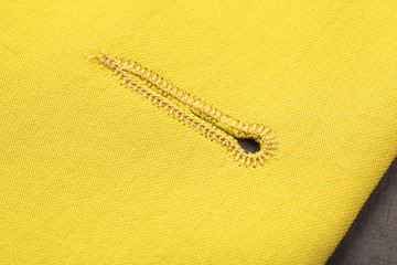 type of fastener on a slotted loop, processed by machine seam and a button covered with the main fabric of yellow color