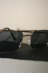 black sunglasses with a gold frame on a beige background