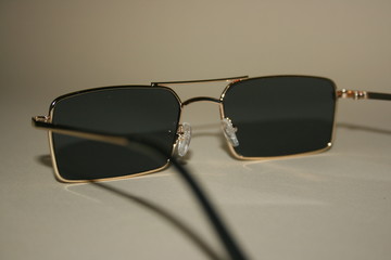 black sunglasses with a gold frame on a beige background