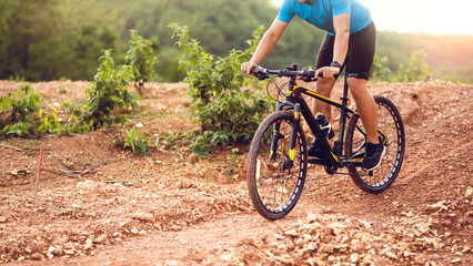 Fototapeta premium Close up mountain bikes cyclist cycling, Asian man athlete riding biking on rocky terrain trail, extreme sport wear gear uniform helmet, exciting freedom outdoor sunset nature healthy active lifestyle