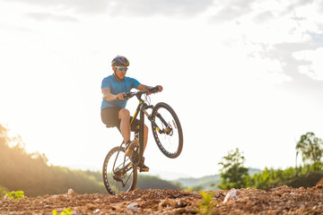Mountain bikes cyclist cycling, Asian man athlete riding biking jumping on rocky terrain trail,...