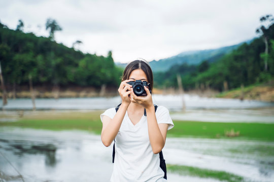 Asian attractive young woman traveler tourist hiking bag pack hipster standing using camera taking picture of mountain valley nature landscape scenery exploring feeling peaceful joyful happy success