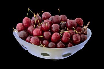 Tasty dark red cherries in a glass vase isolated on black