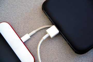 Smartphone connected to a power bank. Way to charge the battery of a mobile phone without connecting to electricity. Tools for telecommunting
