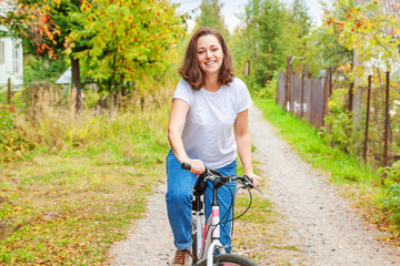 Fototapeta premium Young woman riding bicycle in summer city park outdoors. Active people. Hipster girl relax and rider bike. Cycling to work at summer day. Bicycle and ecology lifestyle concept.