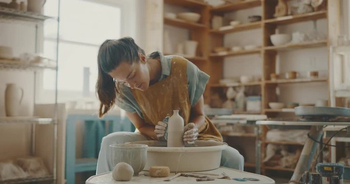 Creative woman making clay vase in pottery studio, hands and clay, handmade pottery