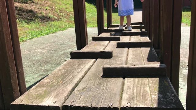Ni&ntilde;a andando sobre estructura de madera.