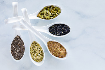 Super seeds in wonton spoons against a bright marble background with copy space to the right.