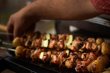 Hand manipulating skewers on the barbecue grill