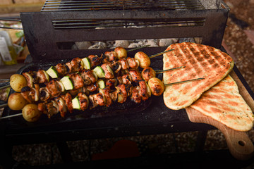 Freshly grilled meat and vegetable skewers with flat bread on outdoor barbecue