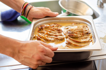 cooking restaurant. hand holding oven pan with pork chops and sauce