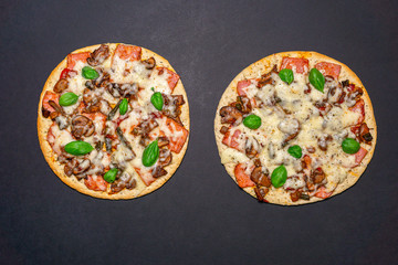 two pizza with mushrooms, ham and Basil on a black background. Copy space. The view from the top. flat lay