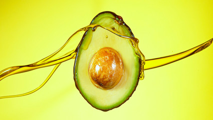 Fresh cut avocado with oil stream. Concept of healthy fruit also useful in cosmetics.
