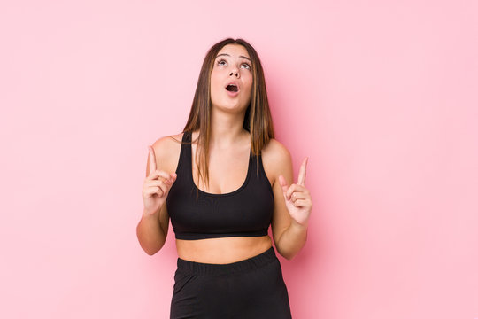 Young fitness caucasian woman isolated pointing upside with opened mouth. © Asier
