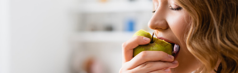 panoramic shot of woman with closed eyes eating apple
