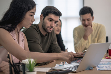 Business team during meeting conference are working documents about the marketing plan and finance sales report of the company with laptop computer