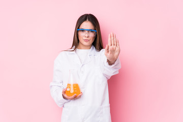 Young chemical woman isolated standing with outstretched hand showing stop sign, preventing you.