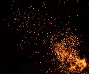 Selbstklebende Fototapeten Feuerflammen mit Funken auf schwarzem Hintergrund, Nahaufnahme © Lukas Gojda