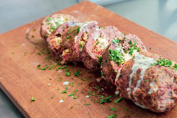 sliced wrapped burger roll on wooden cutting board