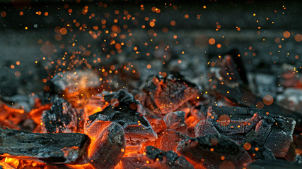 Barbecue-Grillgrube mit glühenden und brennenden heißen Holzkohlebriketts, Nahaufnahme