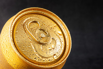Closed tin can, close-up top view. Golden color, water drops on the can.