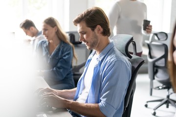 Team Working At Desks In Busy Office