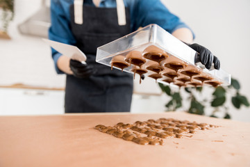 Confectioner girl holds form for candy made of Belgian chocolate