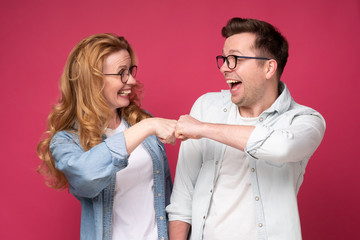 Caucaisan woman and man, friends or coworkers bumping fist showing positive emotions and peace. Studio shot