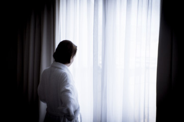 Silhouette of woman with bathrobe in front of a window