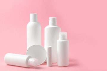 Set of white cosmetic bottles and jars on pink background with place to add text