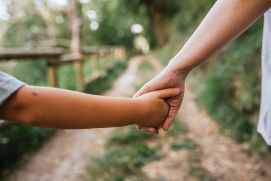 close-up of mother and son holding hands with the background of a field