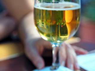 Frisches Bier im Biergarten mit Spiegelung der Rosen im Glas und Unschärfe im Hintergrund