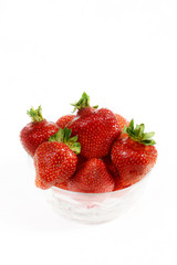 Sweetest and most beautiful strawberries in red berries, isolated on white background. Red juicy strawberries lie in a transparent plate on an isolated white background