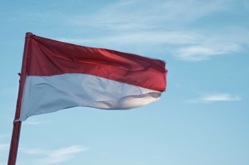 Fototapeta na wymiar indonesian flag flutter over the blue sky, available space for text